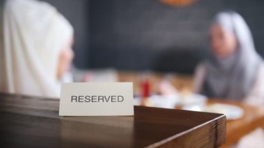 Tablo ayrılmış işareti. Arka plan üzerinde oturan ve konuşurken iki Müslüman kadın