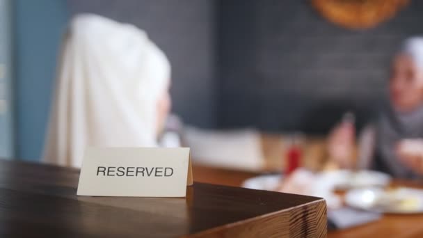 Panneau réservé sur la table. Deux femmes musulmanes assises sur le fond — Video