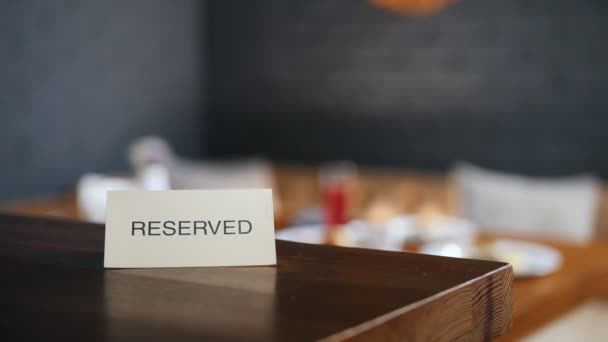 Reserviertes Schild auf dem Tisch. zwei muslimische Frauen setzen sich an den Tisch im Hintergrund — Stockvideo