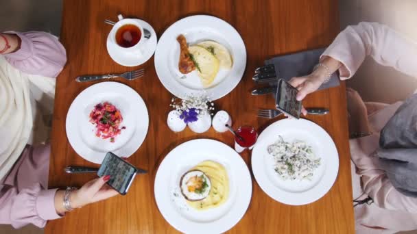 Zwei muslimische Frauen in einem Restaurant. Teller mit einem Essen — Stockvideo