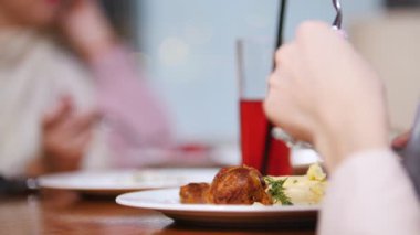 Yemek yeme bir restoranda oturan bir Müslüman kadın. Eti bıçakla kesme ve meyve suyu alarak. Yakın çekim