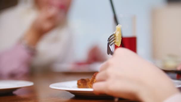 Una mujer musulmana sentada en un restaurante comiendo el plato. Cortar la carne con un cuchillo — Vídeos de Stock