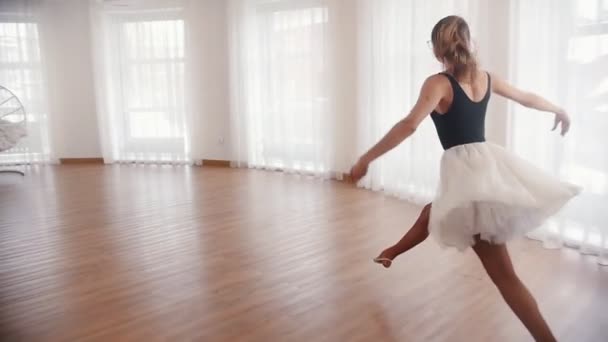 Молода красива жінка балерина біжить вгору і стрибає, виконуючи розкол в повітрі — стокове відео
