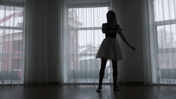 Un estudio en Crepúsculo. Una silueta de bailarina joven entrenando su spinning — Vídeo de stock