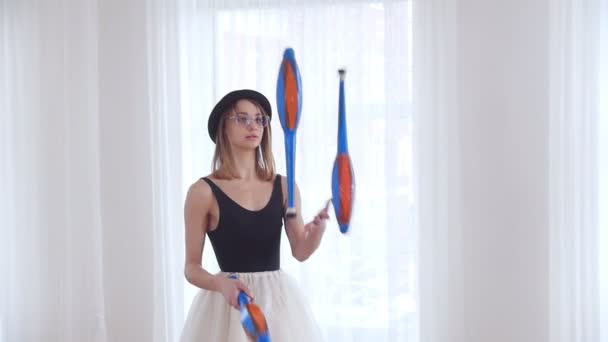 Ung kvinna i en svart hatt jonglering i ljusa studio — Stockvideo