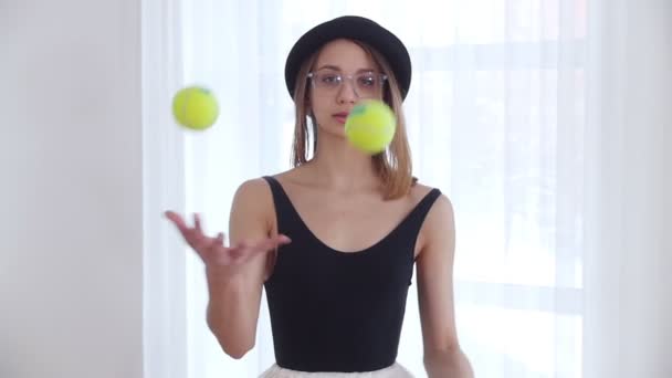 テニスのボールでジャグリングのメガネの若い女性 — ストック動画