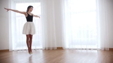 Parlak studio eğitim genç güzel kadın balerin. Atlar ve havada tek ayak üzerinde dönüş gerçekleştirir