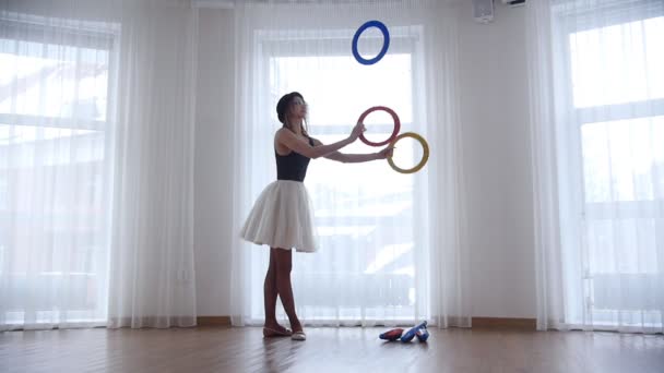 Młoda kobieta baleriny żonglerka z circle obiektów w jasnych studio przez okno — Wideo stockowe