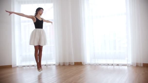 Mooie jongedame ballerina opleiding in heldere studio. Springt en voert de pirouette in de lucht — Stockvideo