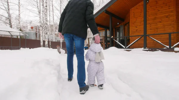 Winter. Jong gezin lopen met hun baby op de besneeuwde binnenplaats — Stockfoto
