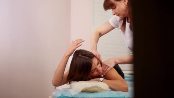 Клініка краси. Молода брюнетка отримує розслабляючий масаж спини — стокове відео