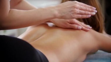 Rahatlatıcı bir sırt masajı alan genç bir kadın. Arkadaki avuç içi ile dokunarak