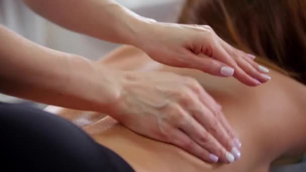 Een jonge vrouw ontvangt een rugmassage. Te tikken op de rug met palmen — Stockvideo