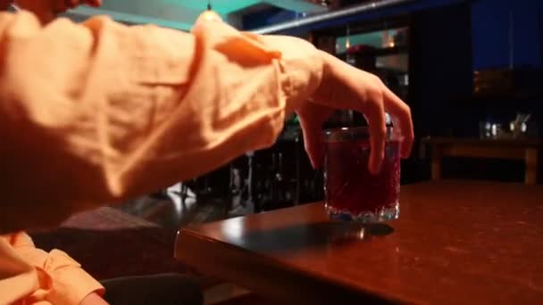 Een man haakt zijn cocktail van de tafel en zitten in de buurt van het gezelschap van zijn vrienden — Stockvideo