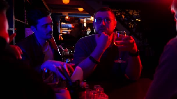 Bar mit Neonbeleuchtung. Freunde, die Zeit miteinander verbringen und reden. Ein Mann mit Brille erzählt Geschichte — Stockvideo