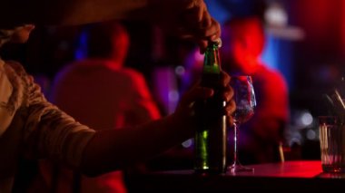 Neon aydınlatma çubuk. Bir adam açık bir şişe bira ve cam dökme