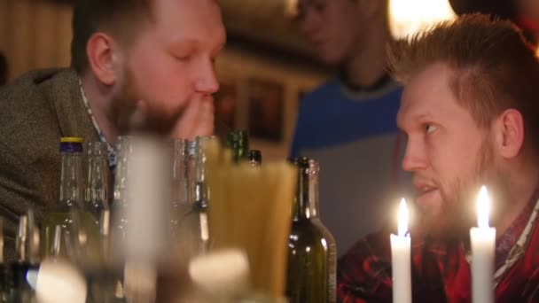キャンドル ライトに照らされたインテリアの上品なバーで一緒にドリンクを飲みながら話している若い男性の友人 — ストック動画