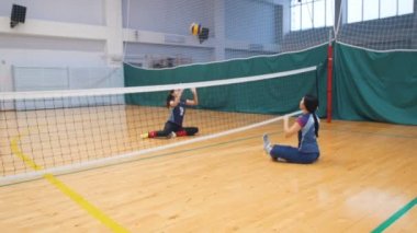 Engelliler için spor. Spor salonu katta oturan ve voleybol oynarken iki genç kadın