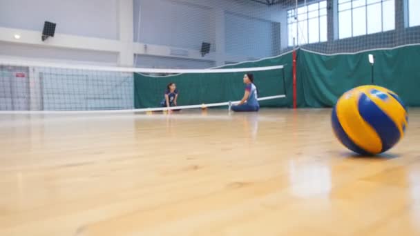 Спорт для инвалидов. Раздавая мяч молодой девушке, сидящей на полу — стоковое видео