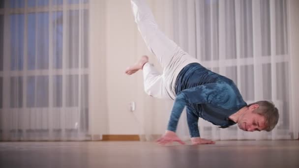 Бойових мистецтв. Капоейра. Професійна людина виконує акробатичні руху, спершись на руки — стокове відео