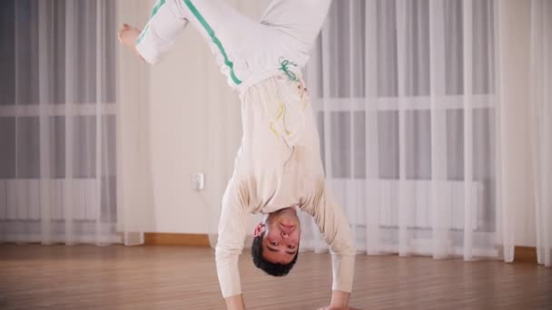 Artes marciales. Capoeira. Un hombre profesional realiza un rodeo apoyado en las manos — Vídeos de Stock