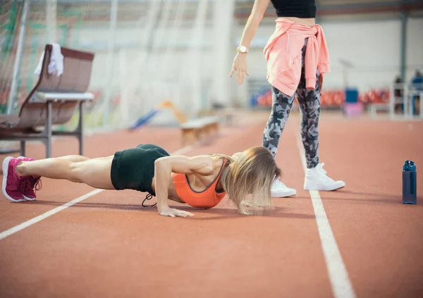 Duas jovens mulheres atléticas se aquecendo na arena esportiva — Fotografia de Stock