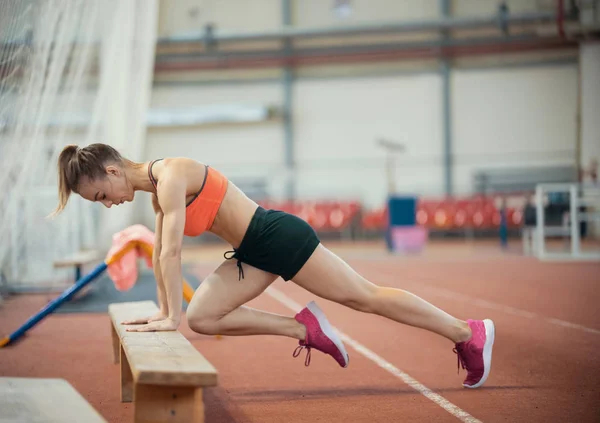 Mujer atlética joven en ropa deportiva haciendo ejercicio usando un banco — Foto de Stock