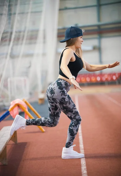 Mulher atlética jovem em leggings aquecimento usando um banco — Fotografia de Stock