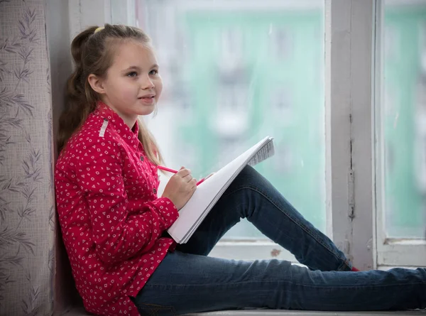 Une petite fille assise sur un rebord de fenêtre — Photo
