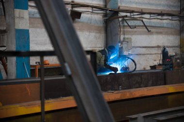 Bir adam onun işyerinde oturan ve bir kaynak makinesi kullanma