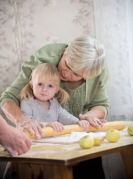 Бабушка печет пирожки со своей внучкой. Роллинг тесто — стоковое фото
