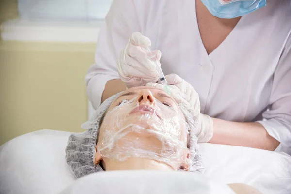 Kosmetologis bekerja dengan wajah klien. Prosedur kosmetik mesoterapi. Melakukan suntikan di dahi. — Stok Foto