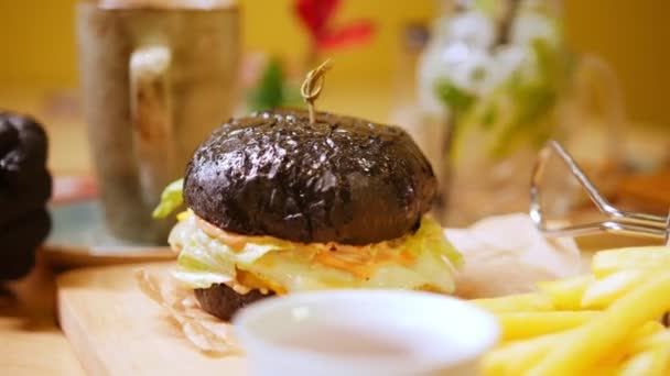 Чорний бургер з беконом і соусом барбекю на дерев'яному столі — стокове відео