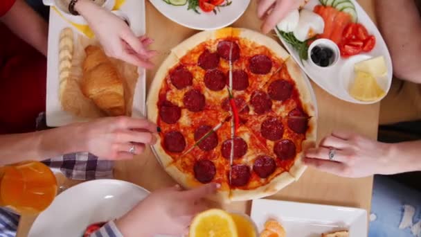 Grupo de amigos sentados en la cafetería. Tomando trozos de pizza pepperoni — Vídeos de Stock