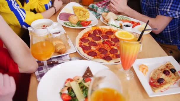 Grupo de amigos sentados en la cafetería. Mesa llena de comida. Tomando trozos de pizza pepperoni — Vídeos de Stock