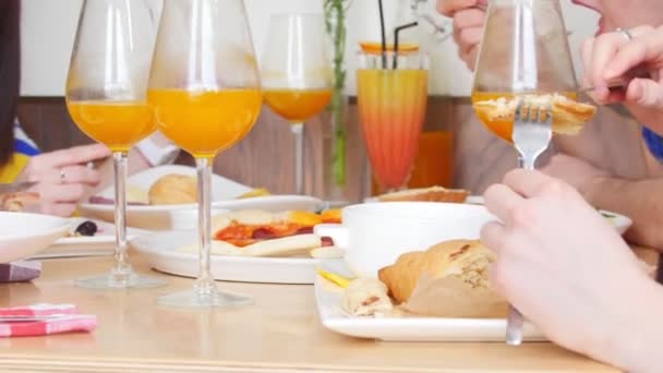 Grupo de jóvenes amigos sentados en la cafetería junto a la mesa y disfrutando de sus comidas — Vídeos de Stock