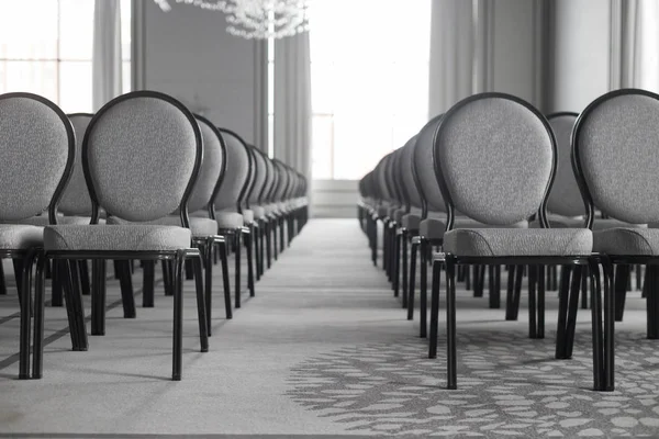 Порожній конференц-зал. Прямі ряди стільців. Симетричний коридор. Монохромний — стокове фото