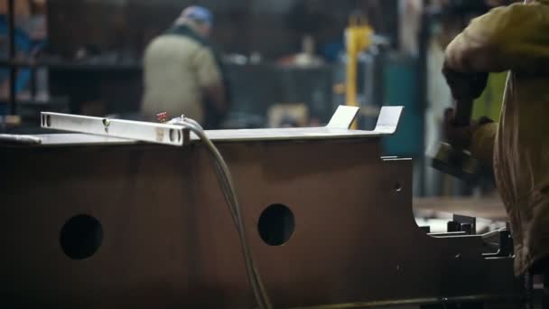 Concept industriel. Des gens qui travaillent sur une usine. Un homme frappe un détail avec un marteau pour le plier — Video