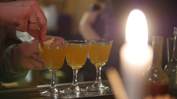 Professional bartender pouring orange drink into glasses