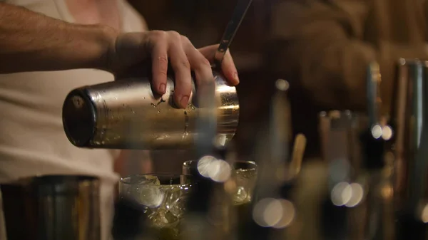 Молодий професійний бармен виливає напій з шейкера в склянку — стокове фото