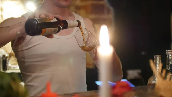 Молодой профессиональный бармен наливает темное пиво в стакан — стоковое фото