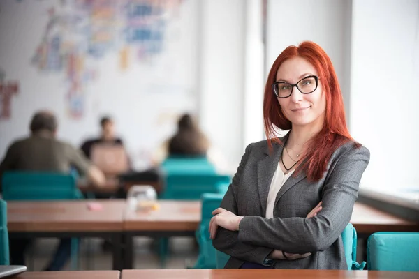 Education concept. Smiling ginger teacher woman in glasses sitting office