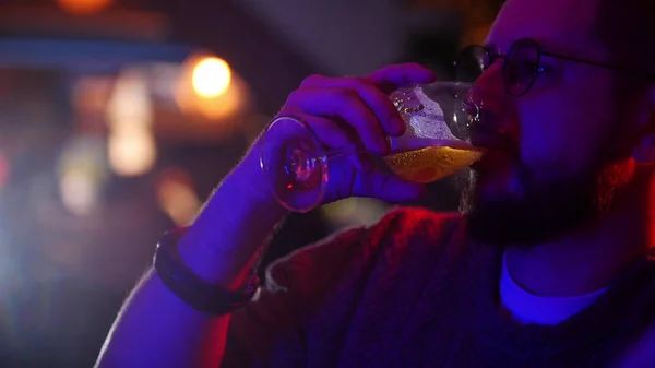 Bar com iluminação de néon. Um homem a beber um copo de cerveja — Fotografia de Stock