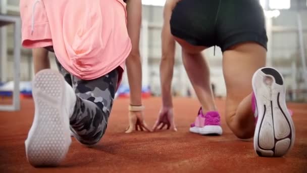 Dos jóvenes se preparan para correr en una pista de atletismo y empezar a correr — Vídeo de stock