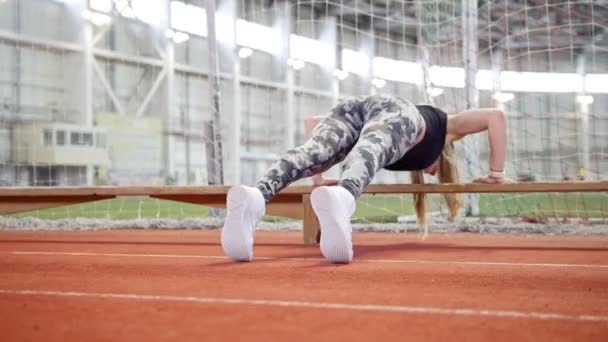Jovem atlética em leggins fazendo flexões usando um banco — Vídeo de Stock
