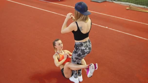 Två unga atletiska kvinnor gör sport övningar. En kvinna som pumpa hennes abs — Stockvideo