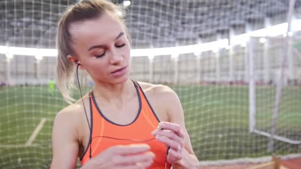 Mujer en forma escuchando música usando auriculares en los deportes y comienza a correr — Vídeo de stock