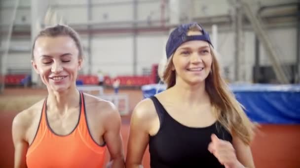 Twee jonge atletische vrouwen vrienden draait op een lopend bijhouden — Stockvideo