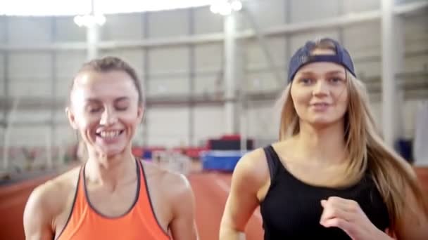 Dua orang teman atlet wanita tersenyum berlari di lintasan lari — Stok Video