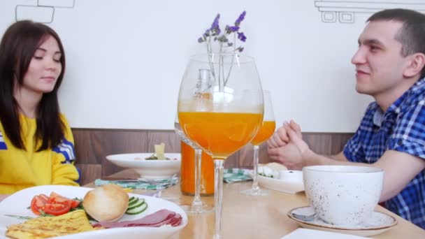Groep vrienden zitten in een cafe en praten. Glas sinaasappelsap op een voorgrond — Stockvideo